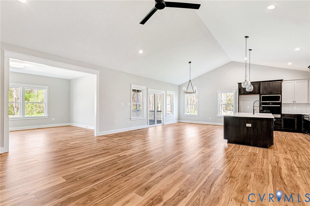 This open-concept living space features hardwood flooring and vaulted ceilings with recessed lighting
