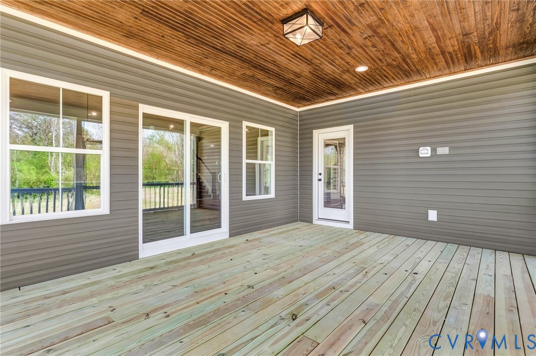 The property features an outdoor patio with a wooden deck, gray siding, and a wood plank ceiling