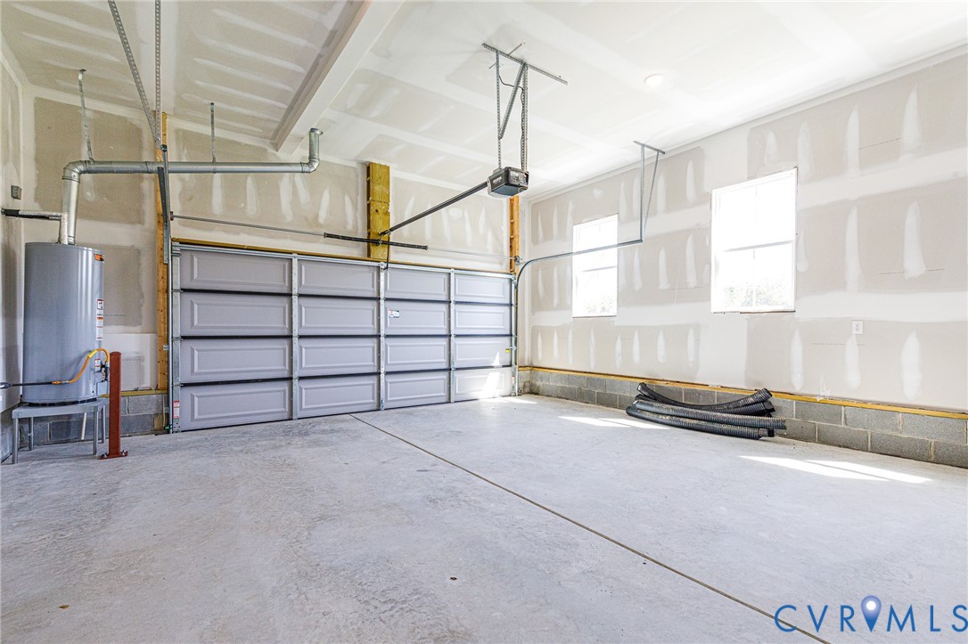 Spacious garage with a concrete floor, a light-colored sectional garage door, and two windows providing natural light