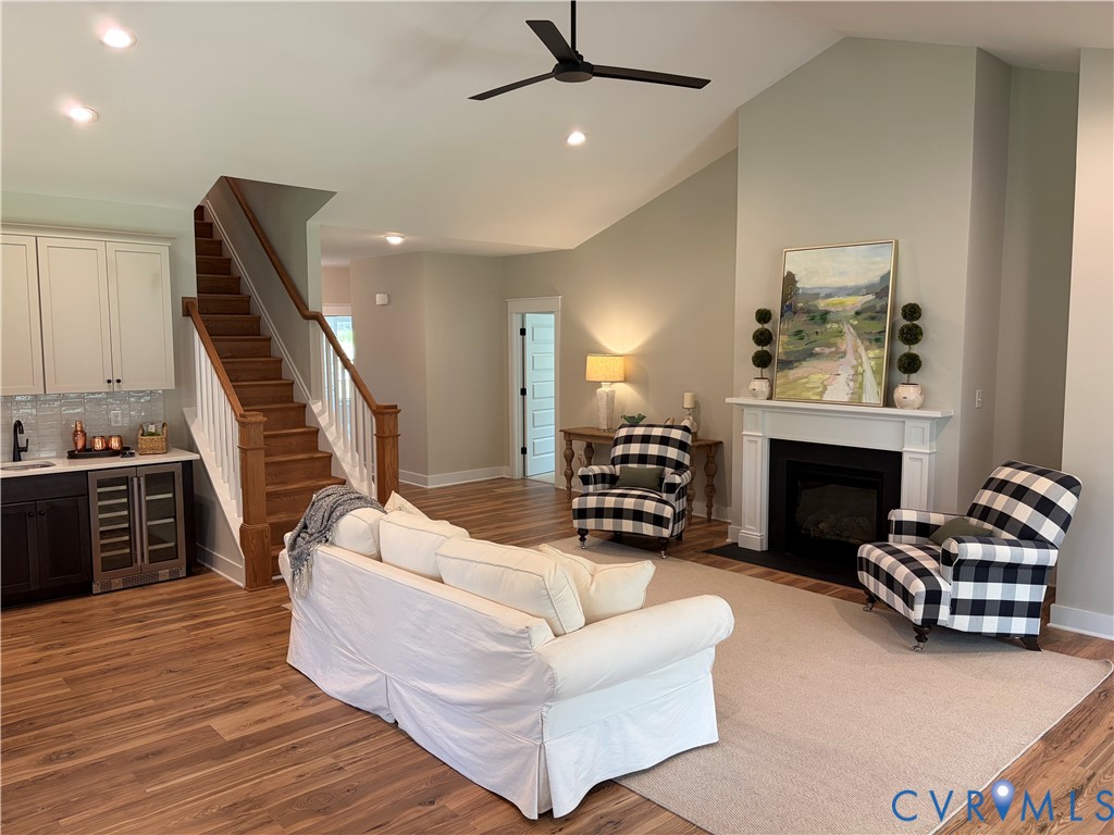 Spacious living area featuring vaulted ceilings, a built-in fireplace with white mantel, and wood-finish flooring