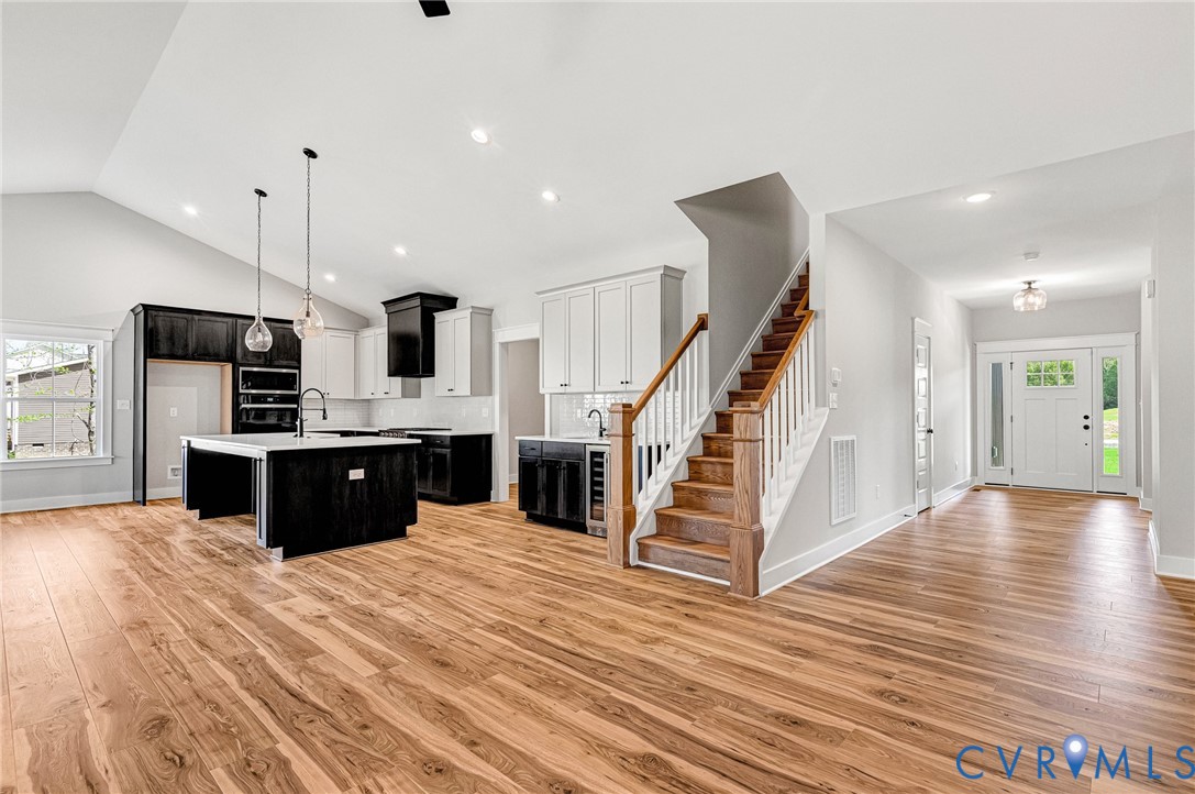 Inviting open-concept interior featuring hardwood flooring, a modern kitchen with a central island, and a prominent staircase
