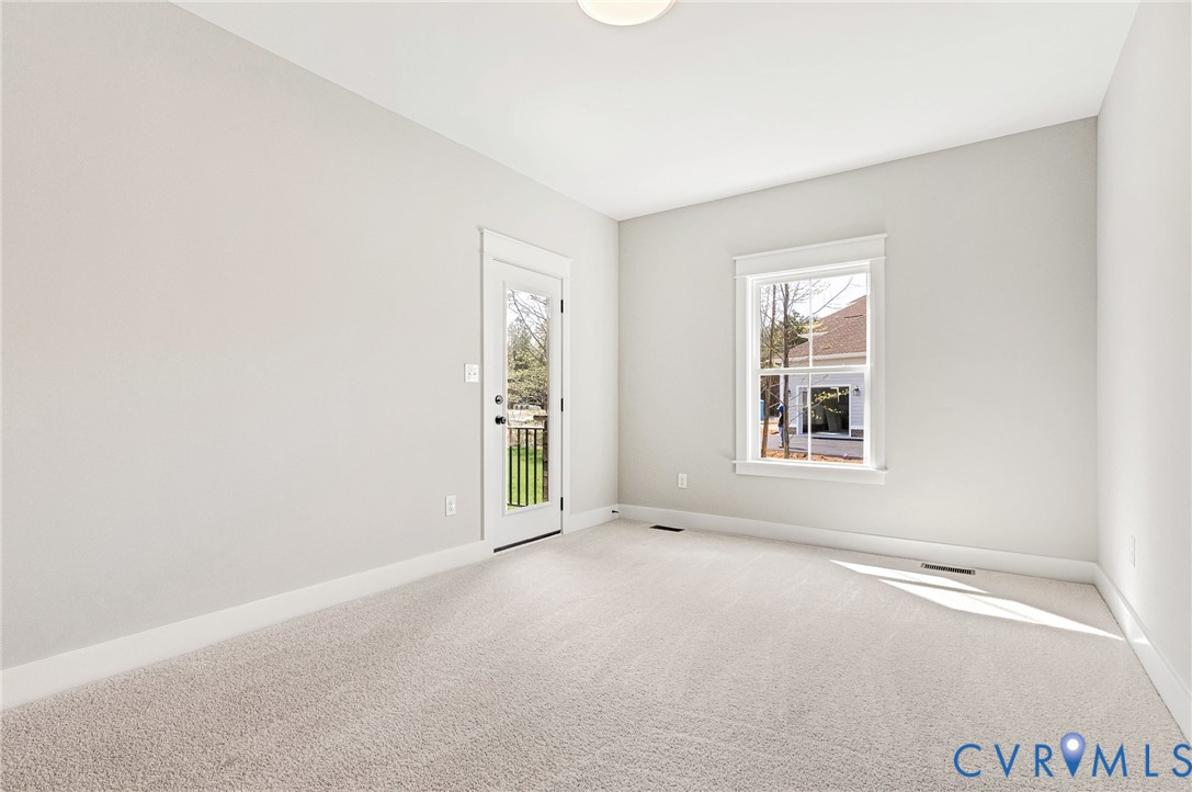 Spacious room with light-colored carpet, a large window, and a door leading to an outdoor area