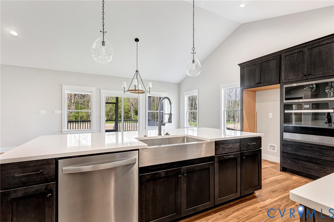The kitchen features a large island with white countertops and a stainless steel farmhouse sink, dark wood cabinetry, and stainless steel appliances