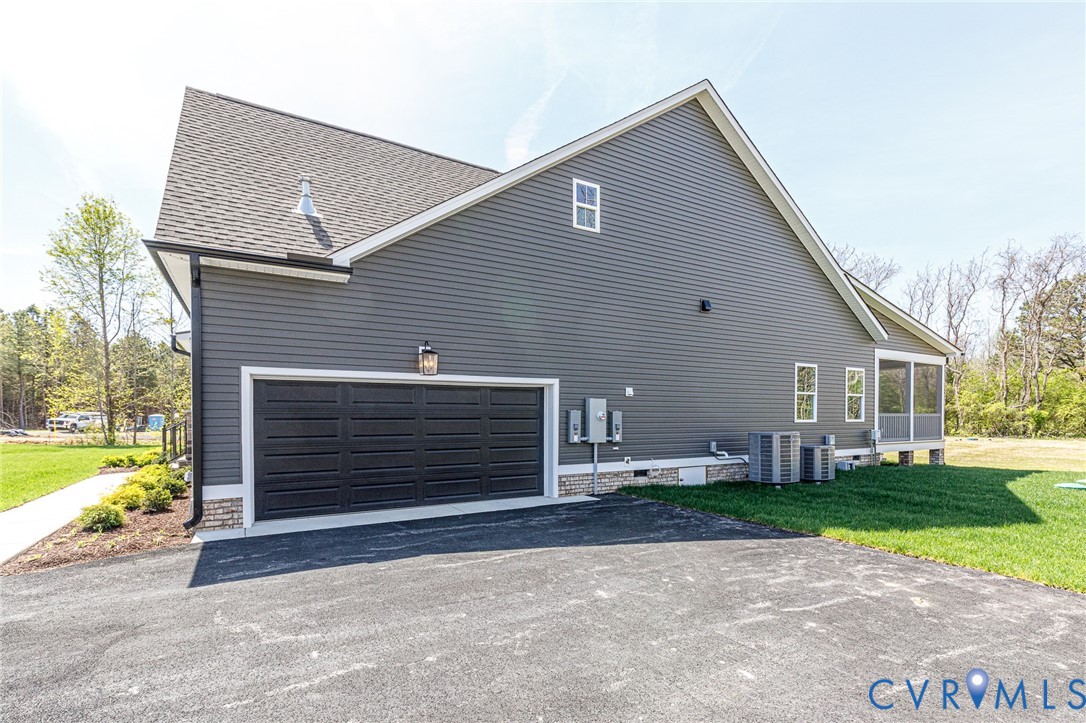 The property features dark gray siding, a black garage door, and a screened porch