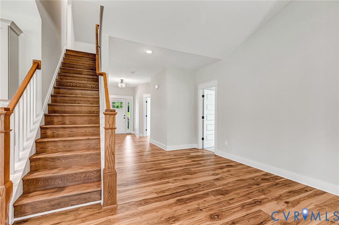 Entryway featuring hardwood floors, a wooden staircase with white risers, and white walls