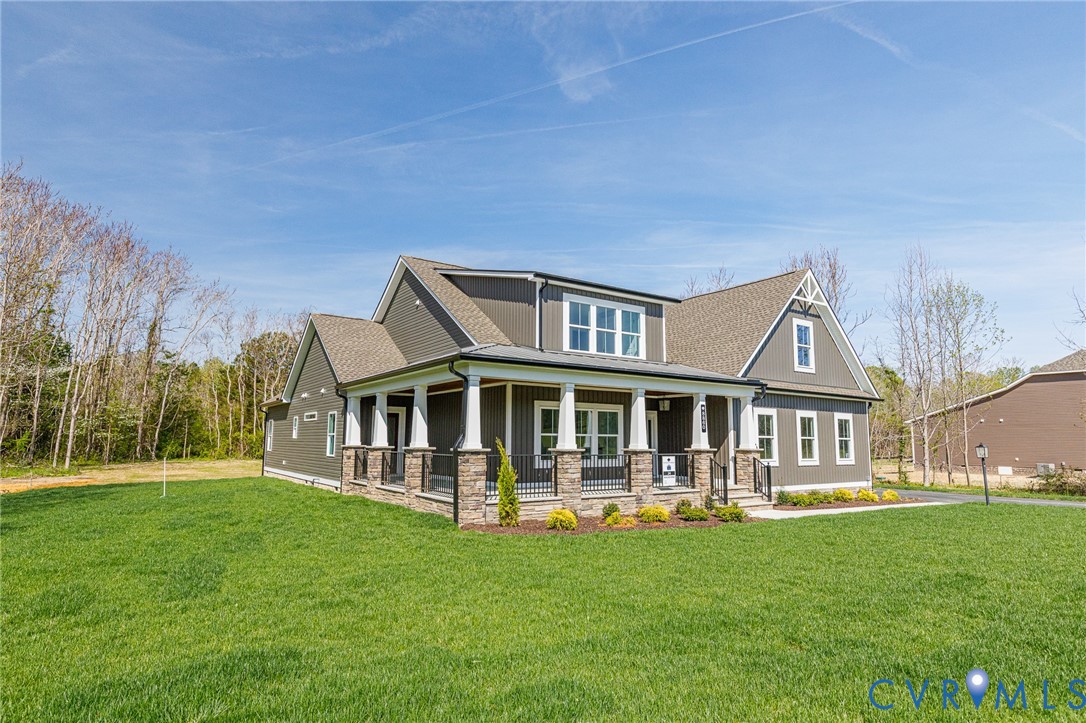 The property features a well-maintained lawn and a covered front porch with white pillars and stone accents