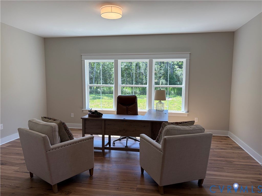 Spacious interior room featuring wood-finish flooring, neutral wall tones, and extensive natural light from a triple window unit