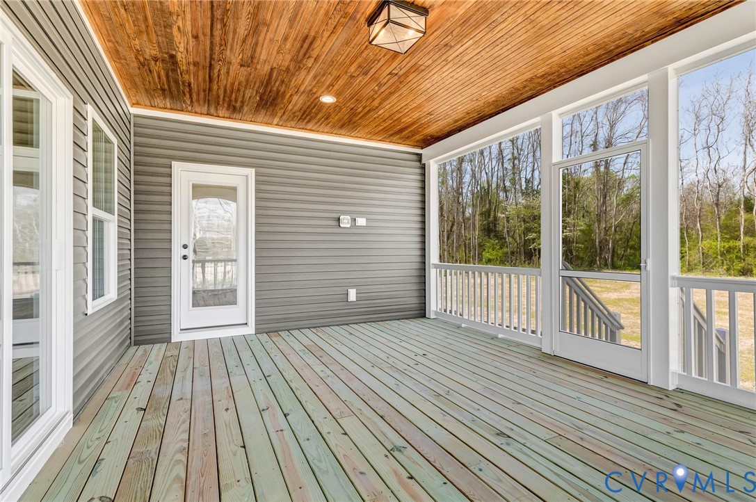 The property features a screened-in porch with a wood plank ceiling and a light fixture, offering an outdoor living space with views of mature trees