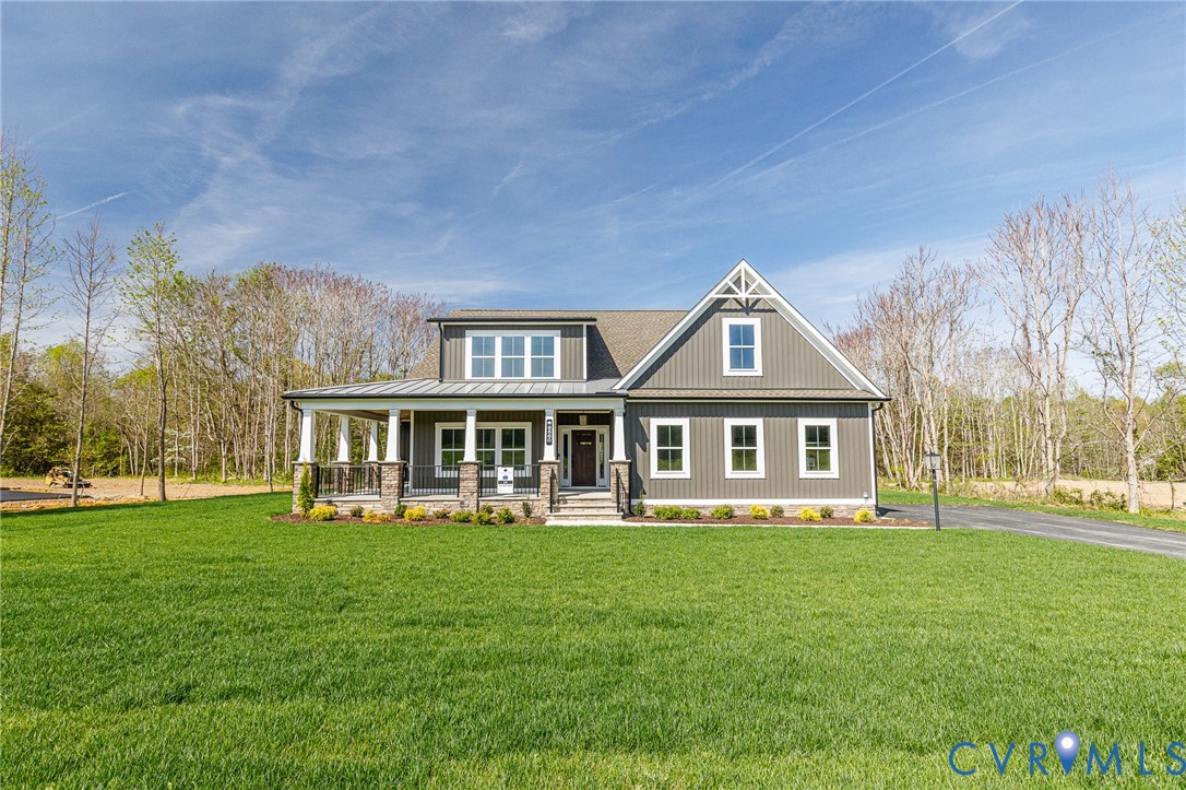 This property features a well-maintained lawn and a welcoming covered porch with stone column bases