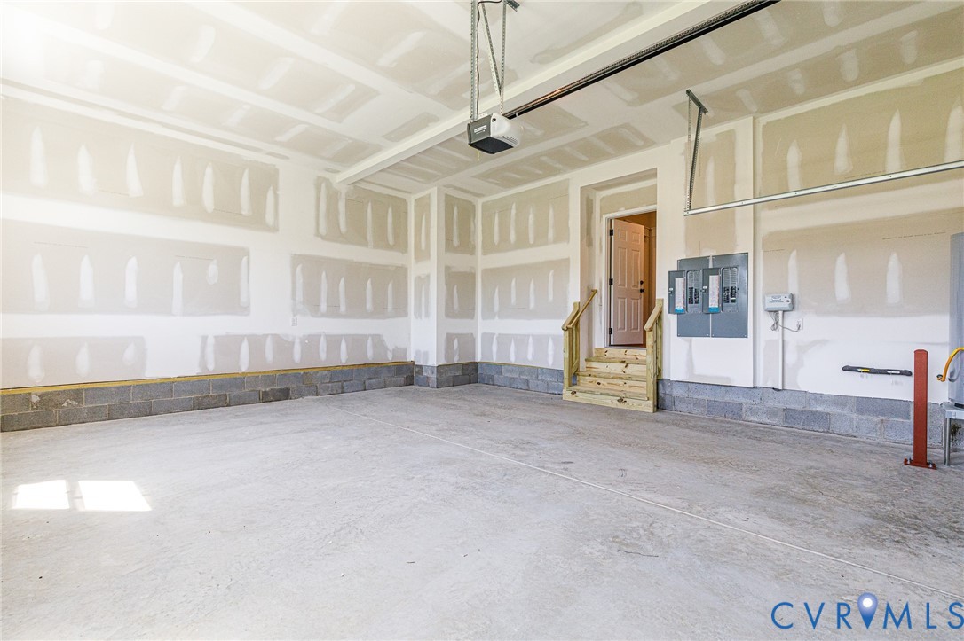 Spacious garage featuring a concrete floor, exposed block foundation, and an interior access door with wooden steps