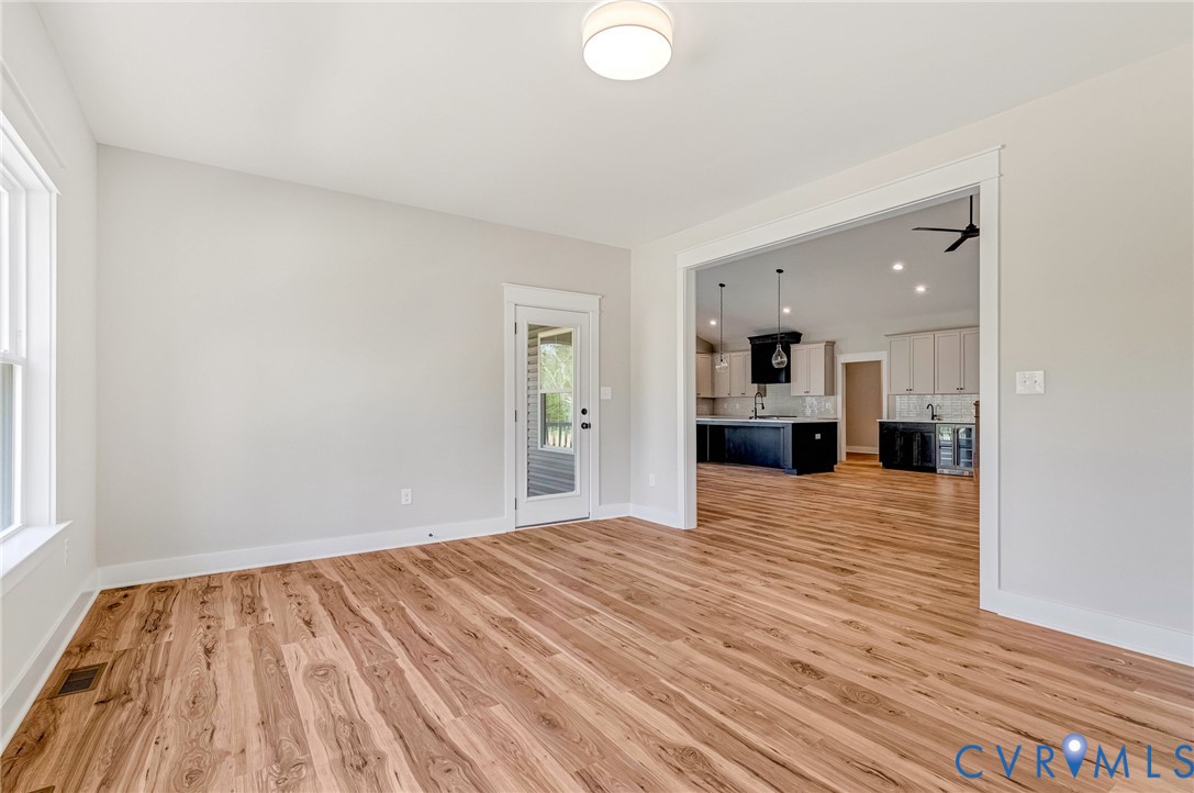 This bright room features a light-colored wall, a window, and wood-style flooring