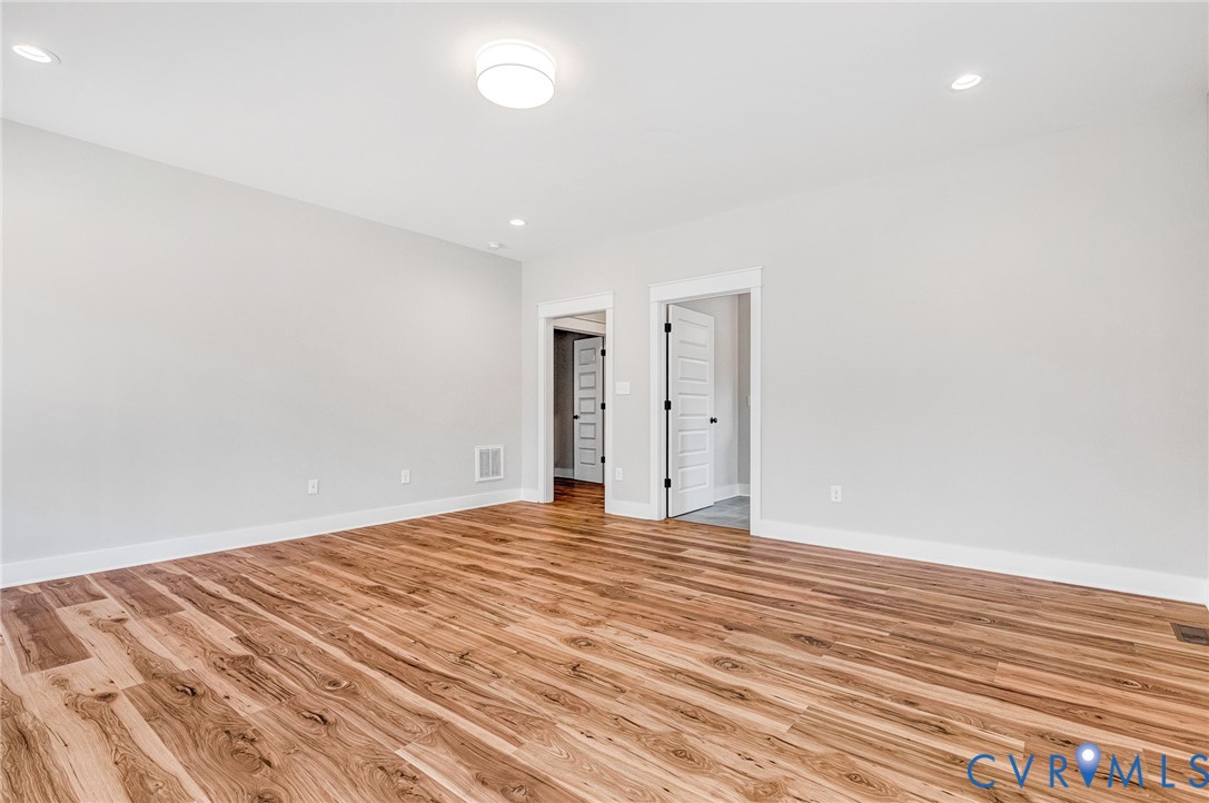 This room features light-colored walls, recessed lighting, and rich wood flooring