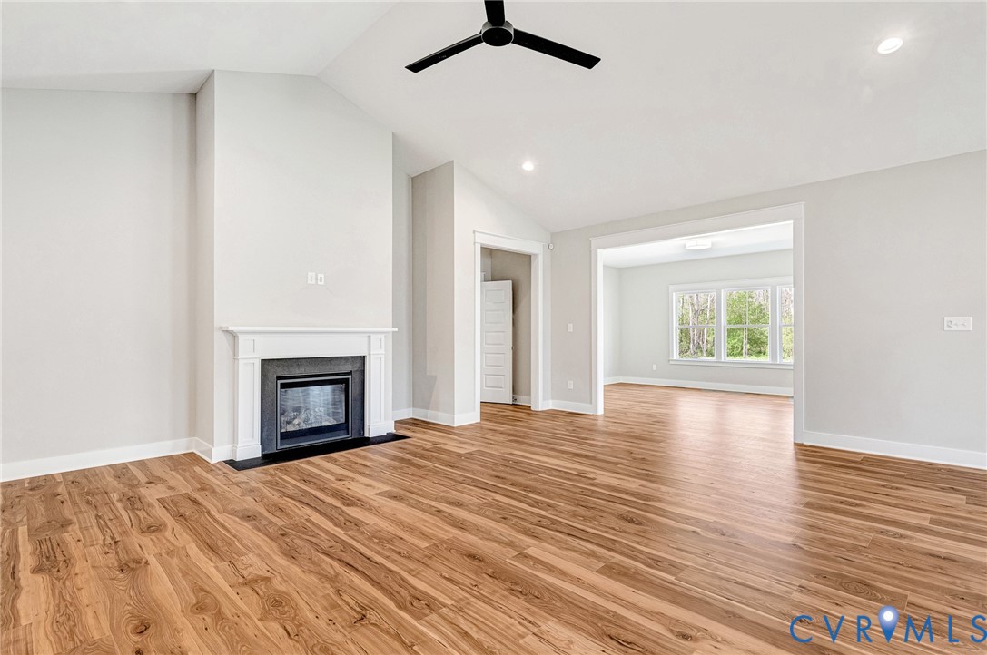 Spacious interior featuring wood-style flooring, a white mantel fireplace, and a black ceiling fan
