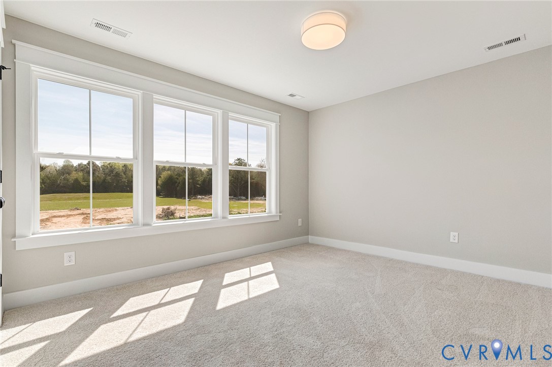 This room features three large windows that provide abundant natural light and views of green fields and trees