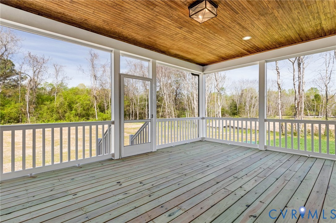 Screened porch featuring a wooden plank ceiling, recessed lighting, and a view of the surrounding trees and natural landscape