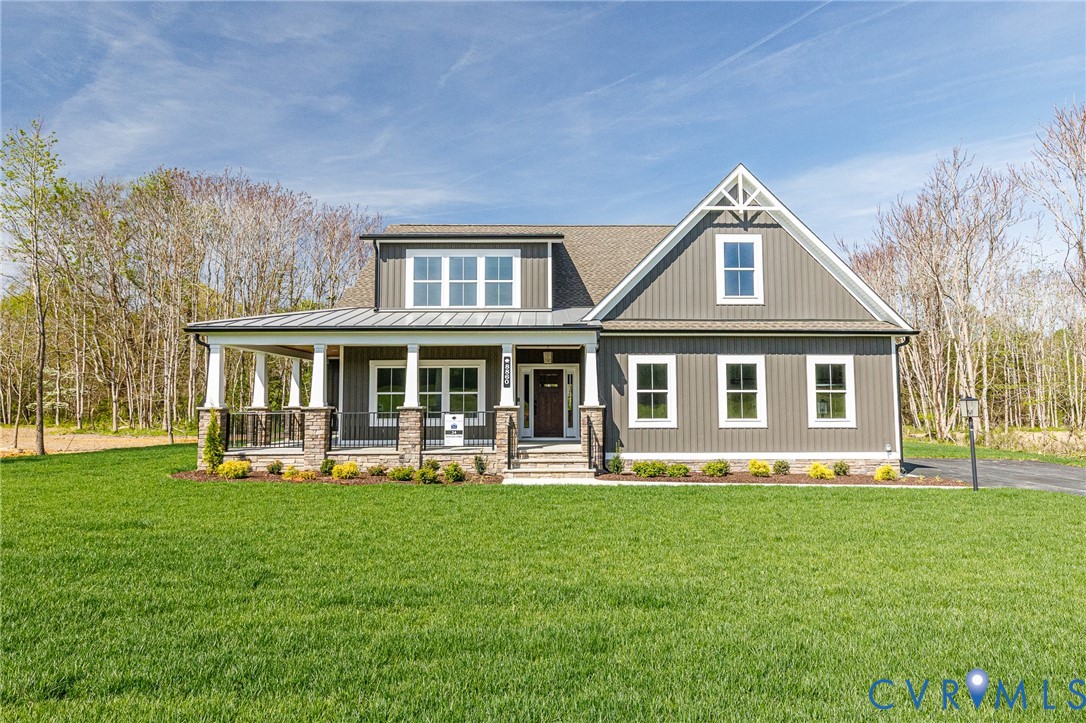 The property features a dark gray exterior with white trim, a covered front porch with white columns and stone accents, and a well-maintained lawn The property features a dark gray exterior with white trim, a covered front porch with white columns and stone accents, and a well-maintained lawn