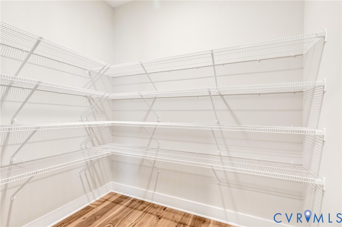 This pantry features extensive white wire shelving and hardwood flooring