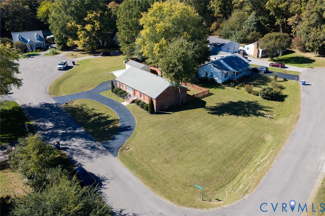 Corner lot with an expansive lawn, brick exterior, asphalt driveway, and mature trees Corner lot with an expansive lawn, brick exterior, asphalt driveway, and mature trees