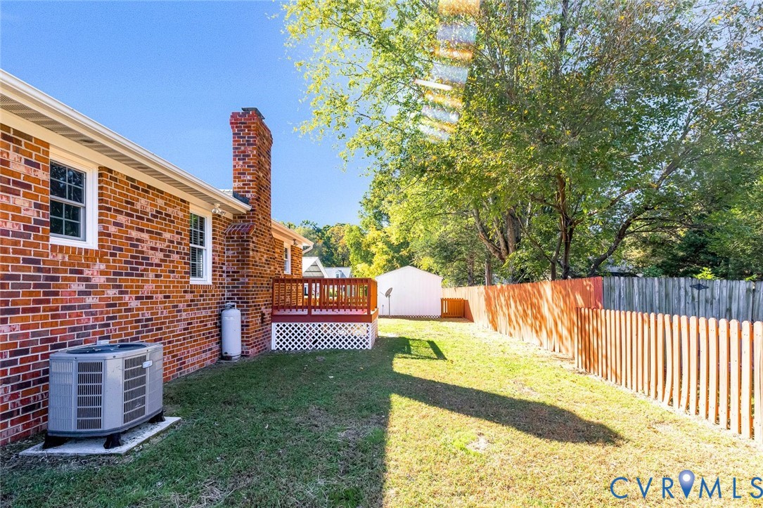 Brick exterior featuring a raised wooden deck, lattice skirting, a detached storage structure, and fenced perimeter Brick exterior featuring a raised wooden deck, lattice skirting, a detached storage structure, and fenced perimeter