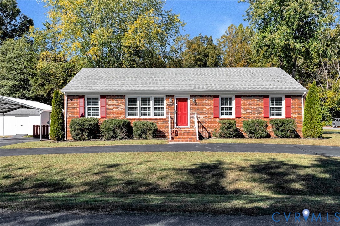 Single-story brick exterior featuring a shingled roof, red decorative shutters, central front entryway with brick steps and railings, and an attached metal-framed carport Single-story brick exterior featuring a shingled roof, red decorative shutters, central front entryway with brick steps and railings, and an attached metal-framed carport