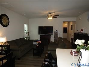 Open-concept interior featuring wood-finish flooring, a multi-speed ceiling fan, and solid surface countertop