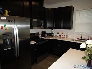 Kitchen featuring dark-finish cabinetry, stainless steel refrigerator, built-in microwave, and solid-surface countertops