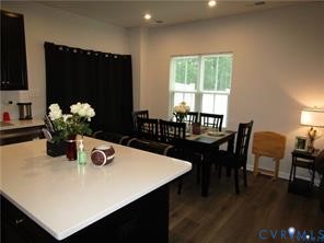 Kitchen island featuring a solid-surface countertop, dark cabinetry, recessed lighting, and wood-finish flooring