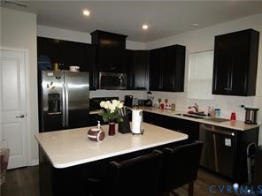Kitchen featuring dark cabinetry, stainless steel appliances, a central island with a solid surface countertop, and recessed ceiling lighting