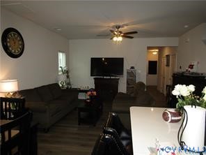 Open-concept interior featuring wood-finish flooring, a multi-blade ceiling fan with integrated lighting, and a neutral color palette