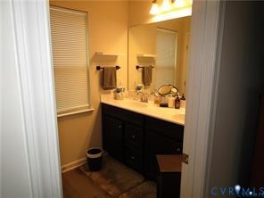 Bathroom featuring a dual-sink vanity with dark cabinetry, light-toned countertop, large wall-mounted mirror, and overhead light fixture