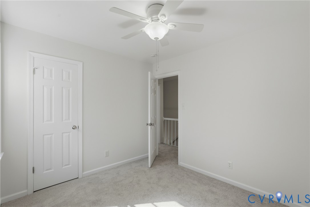 Neutral-toned carpeting, and a ceiling-mounted light fixture with integrated fan