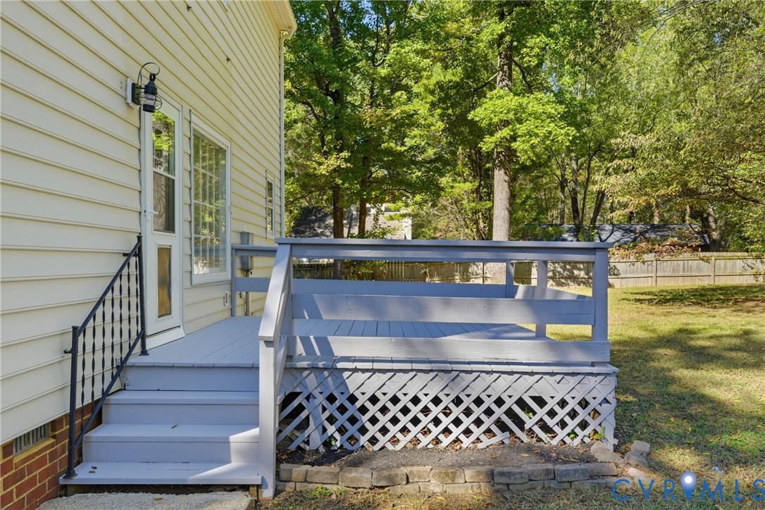 Raised rear deck with painted wood railing, lattice skirting, and wrought-iron staircase handrail