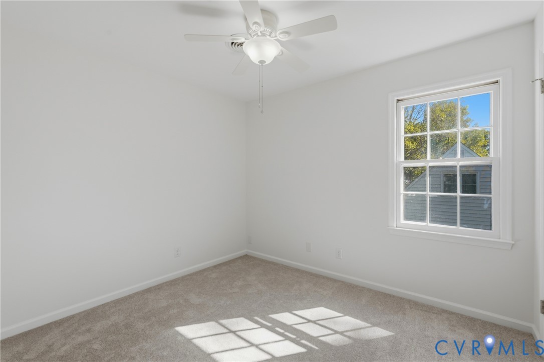 Neutral-toned carpeting, and a ceiling-mounted light fixture with a fan