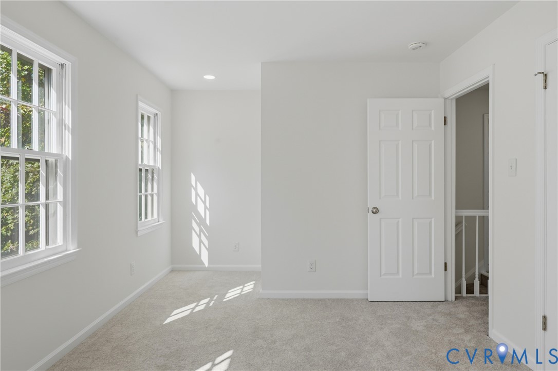 Neutral-toned carpeted flooring, double-hung windows with white frames