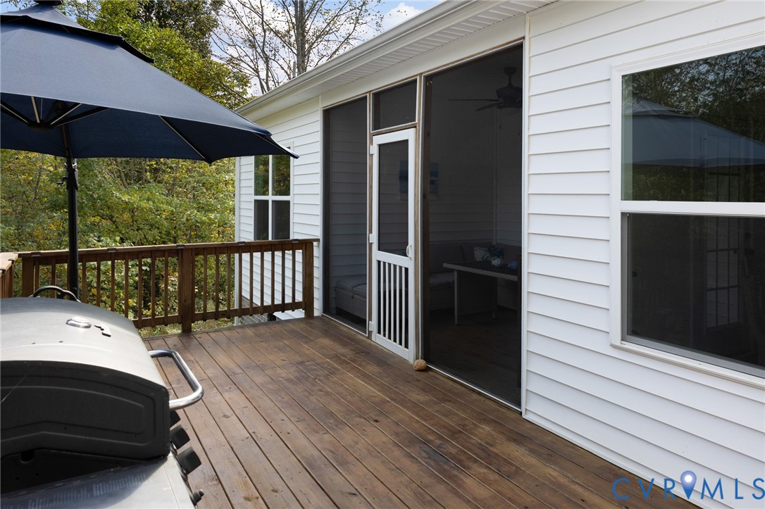 Exterior wood deck featuring a wooden railing and a screened-in porch with a screen door and white lap siding