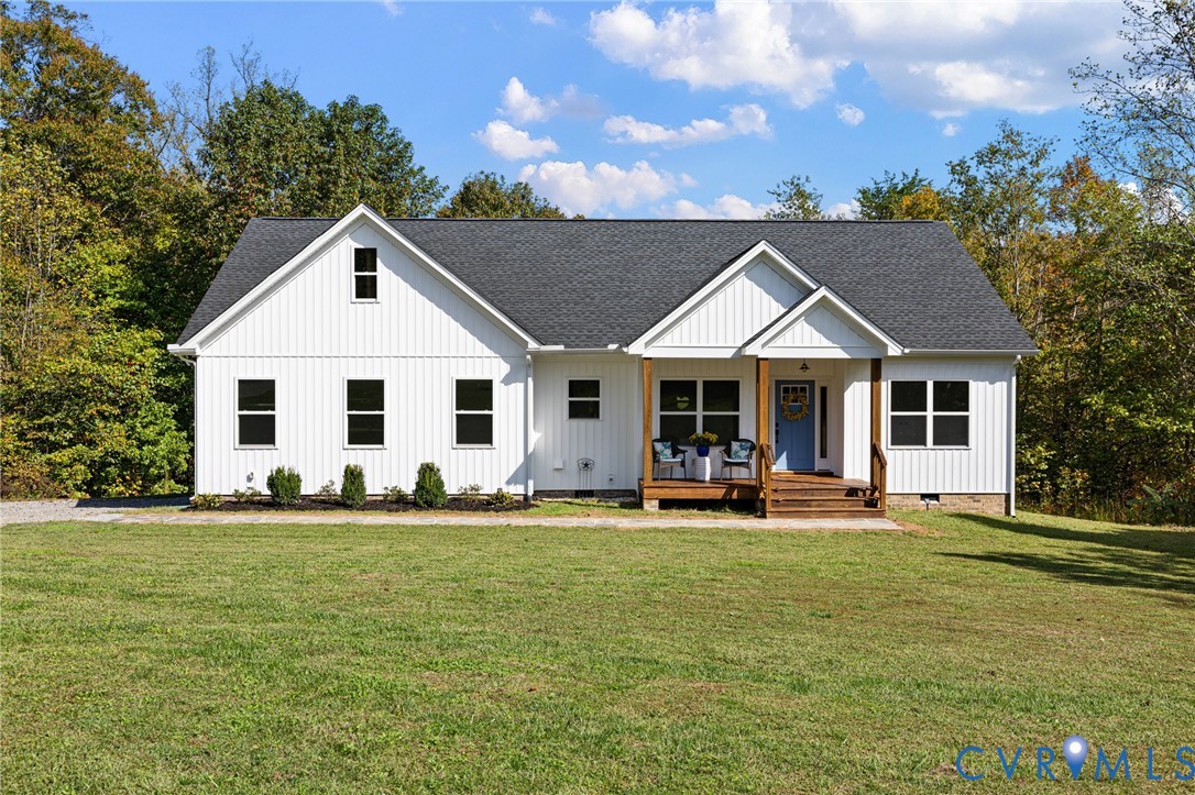 White vertical siding exterior featuring a covered front porch, dark-toned asphalt shingle roof, stone foundation trim, and double-hung windows