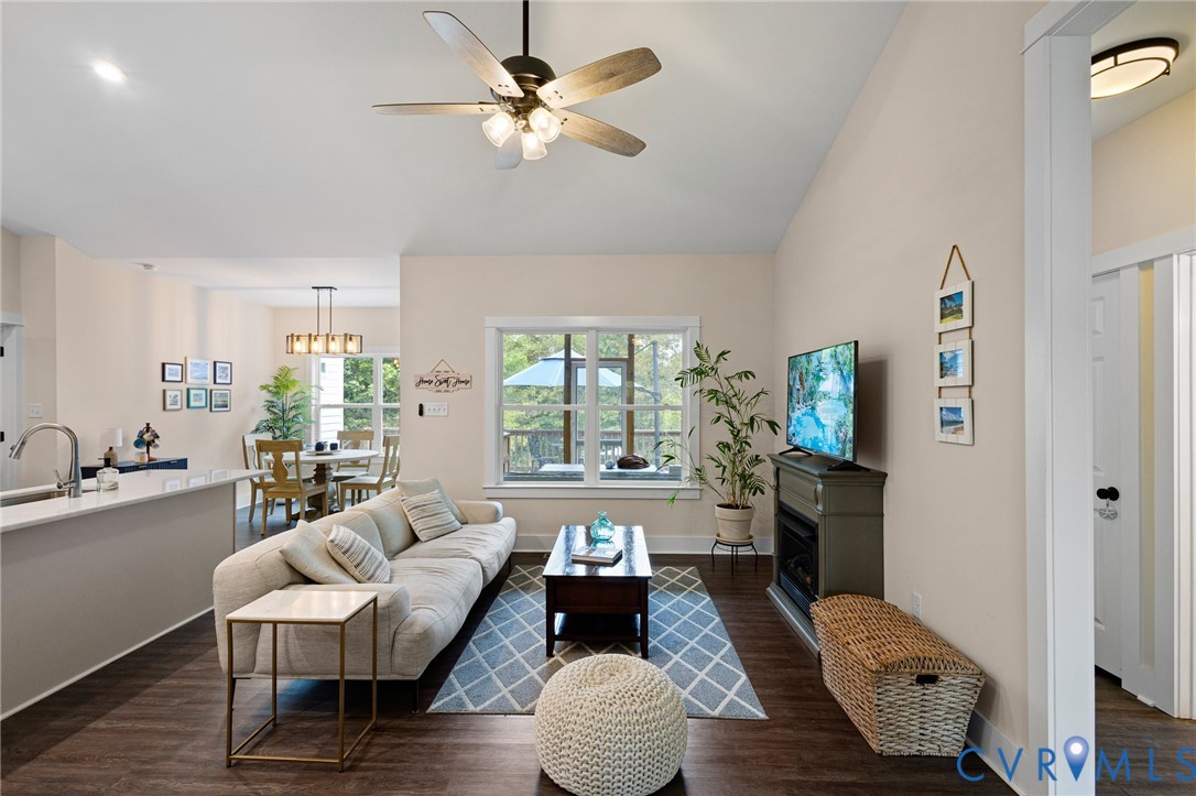 Vaulted ceiling featuring a central multi-blade light fixture, wood-finish flooring, and built-in electric fireplace