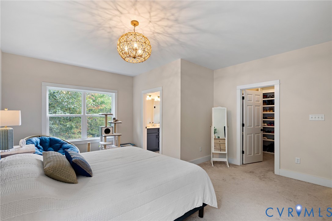 Neutral-toned room featuring a decorative metallic sphere pendant light, walk-in closet with built-in shelving, and window with natural outdoor scenery