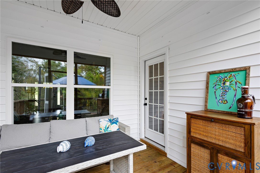 Covered patio featuring white horizontal siding, wood-finish flooring, a ceiling fan, and a glass-paned door