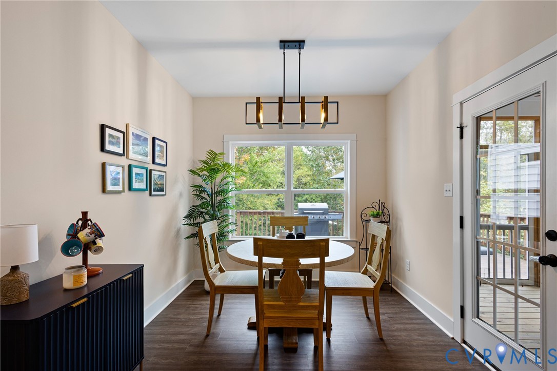 Dining area featuring wood-finish flooring, a contemporary geometric pendant light, a large window, and a glass-paneled exterior door