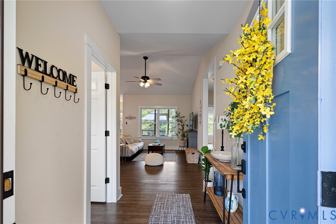 Entryway featuring wood-finish flooring, a blue front door with an inset window, and a vaulted ceiling with a multi-light ceiling fan