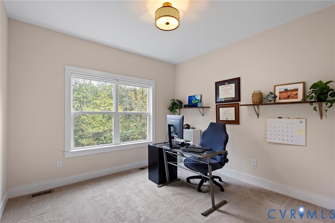 Neutral-toned interior featuring wall-to-wall carpeting, dual-pane window with white casing, and a drum-style ceiling light fixture