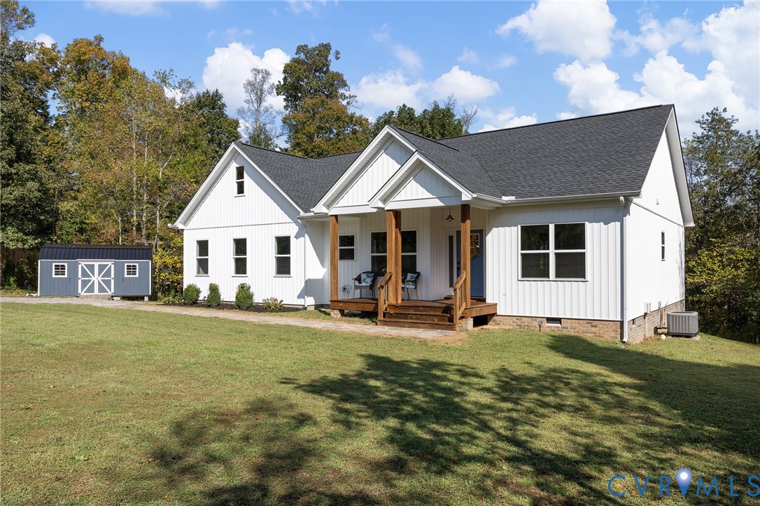 Vertical white siding exterior featuring a gable-roofed covered porch with timber posts, an attached storage structure, and a concrete foundation