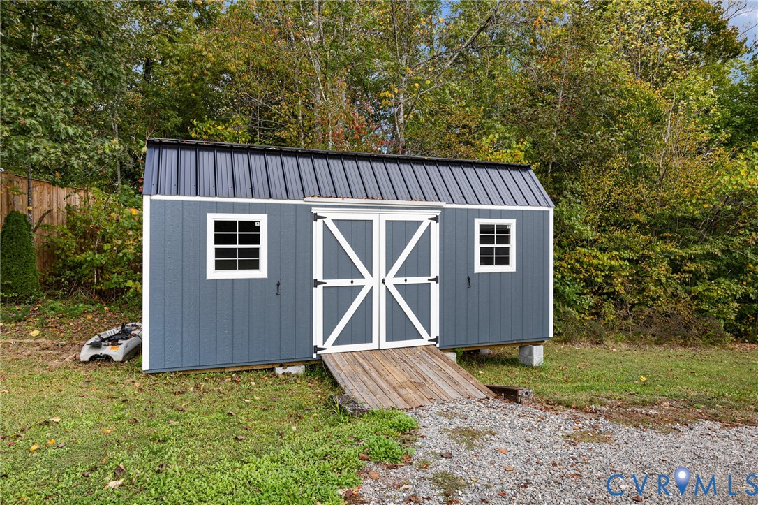 Outbuilding featuring vertical siding, metal roofing, double-door entry, multi-pane windows, and a wood ramp
