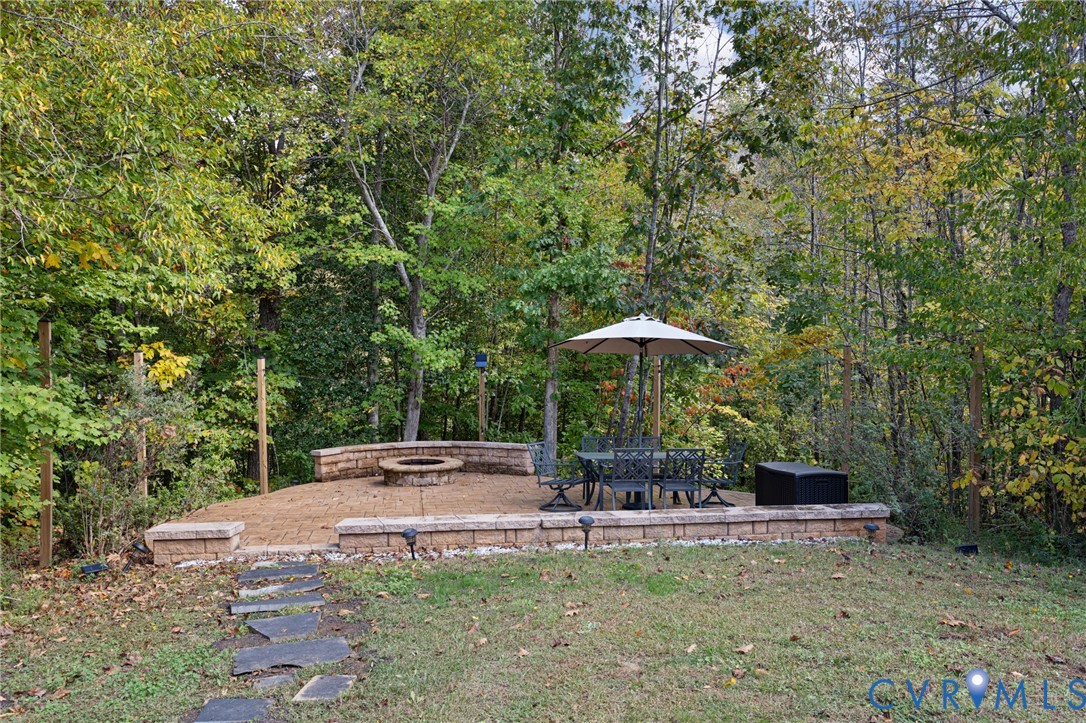Flagstone pathway leading to a paved patio featuring a built-in stone fire pit and tiered retaining walls