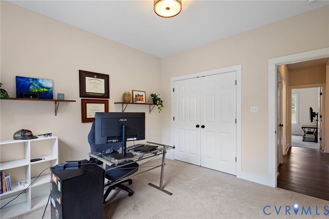 Room featuring neutral wall paint, plush carpeting, double-panel closet doors, and an overhead flush-mount light fixture