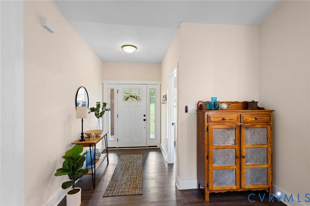 Entryway featuring white front door with sidelights, wood-finish flooring, and flush-mount ceiling lighting