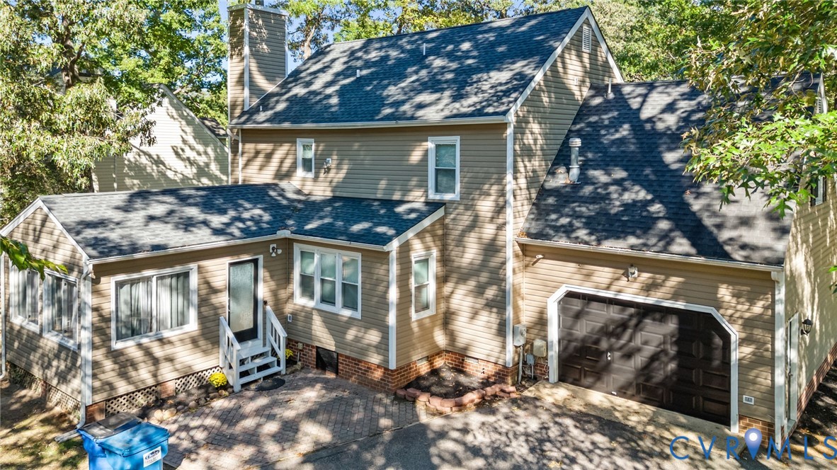 Two-story siding exterior featuring a brick foundation, asphalt shingle roof, attached single-car garage, and a brick-paved patio