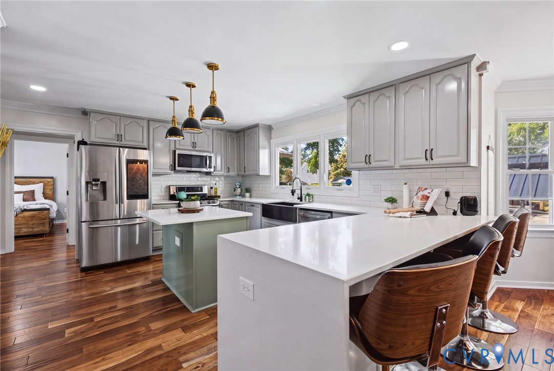 Kitchen featuring white quartz countertops, grey cabinetry, stainless steel appliances, a farmhouse sink, and wood-finish flooring