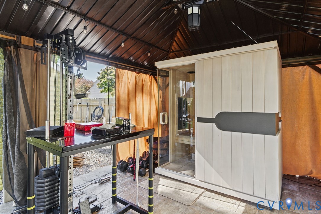Covered outdoor structure featuring a metal roof, integrated overhead lighting, and a sauna enclosure